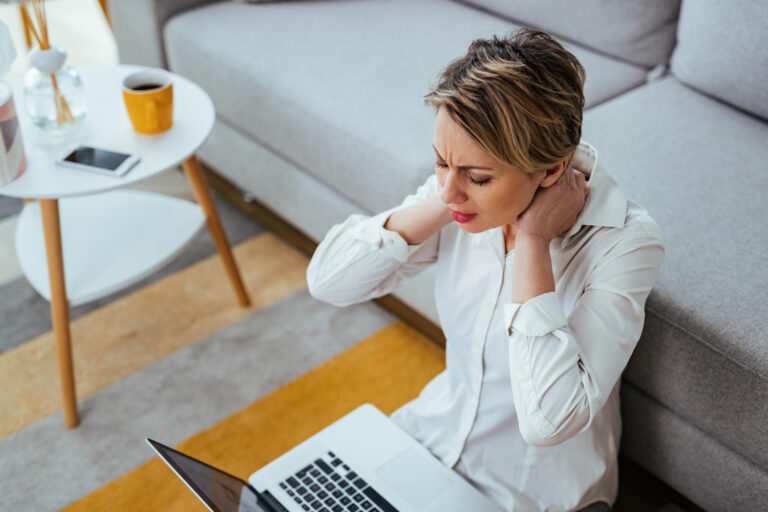 Femme souffrant de douleurs cervicales pouvant être dues à une mauvaise posture ou au tech neck.